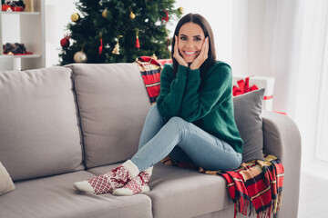 Photo of sweet pretty girl wear xmas green pullover smiling arms cheeks sitting couch indoors home...