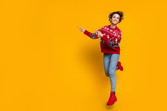 Full length photo of nice girl dressed red jumper flying indicating at christmas offer empty space isolated on yellow color background