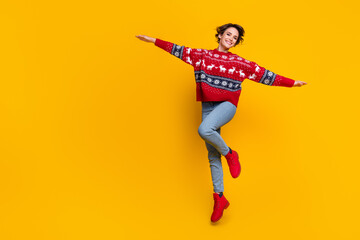 Full length photo of dreamy optimistic girl dressed red jumper flying holding palms like wings isolated on yellow color background - obrazy, fototapety, plakaty