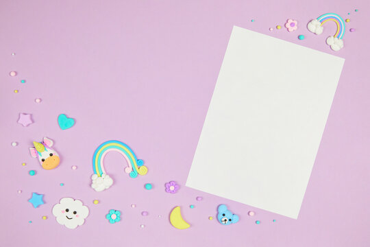 Blank white card on pastel purple background with frame of cute kawaii air plasticine handmade cartoon animals, stars, rainbows. Empty photo frames, baby's photo book, scrapbooking design template
