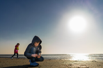 Boy with a girl walks around the lake on a summer day and collected seashells on a beach