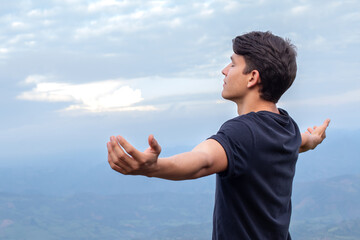 Young Man Breathing Fresh Air and Embracing the Majesty of Nature with Outstretched Arms