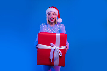 Photo of excited cheerful positive girl wear stylish ugly sweater receive unexpected gift box isolated on blue color background