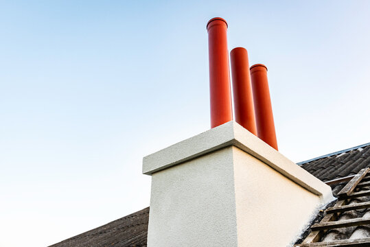Chimney from orange pipes on roof of house.