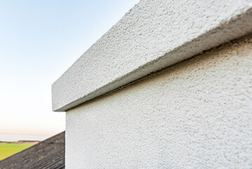 Applying white seamless concrete pebble-dash plaster on chimney. © Natallia