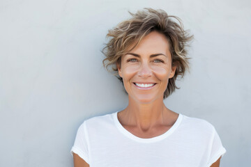 Smiling middle age woman wearing white shirt. - obrazy, fototapety, plakaty