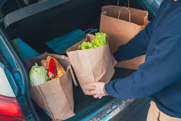 man hands with groceries bags put it in car trunk