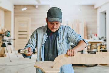 Carpenter works with wood in carpentry workshop. Man doing woodwork professionally