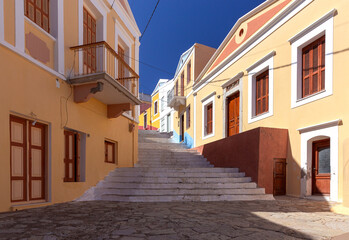 Fototapeta na wymiar Colorful traditional multi-colored houses on a narrow street of Symi island.