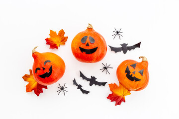 Flat lay of orange Halloween pumpkins and dry leaves, top view