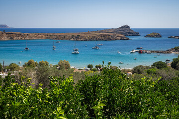 Enchanting Bay in Lindos, Rhodes: A serene Mediterranean retreat where moored boats meet the...