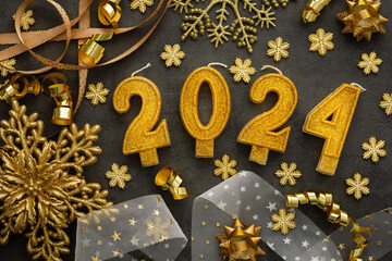 Merry Christmas and Happy New Year 2024, 2024 cake candles and various holiday decorations and ribbons in gold color on black background