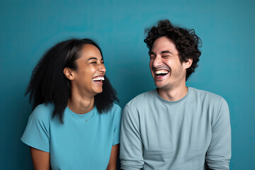 Obraz premium Funny couple laughing cheerfully while sitting together in a studio