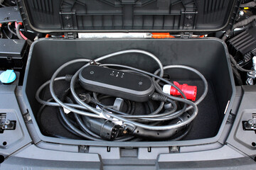 Electric vehicle charging cable in the hood of a car. Electric Vehicle Charging Station in the hood...