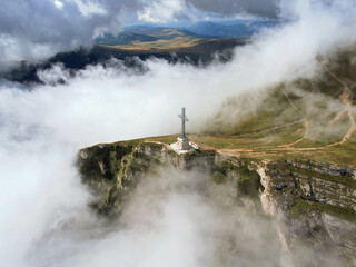 Aerial view of the Heroes' Cross monument, built to honor the Romanian soldiers fallen during WWI. The cross sits on the small summit of the Caraiman Peak, overlooking the town of Bușteni in Romania.