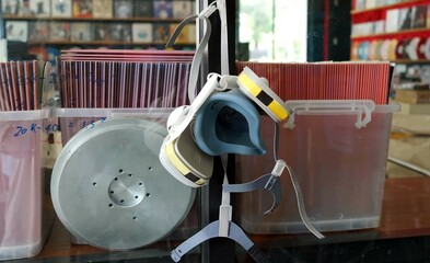 A chemical protection mask hang on a glass wall in the production room a phonograph disk record.