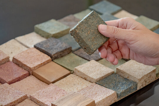 Designer hand picking sample of sustainable decoration material made from rice straw. Natural texture and pattern for interior finishing design or building facade. Alternative material from nature