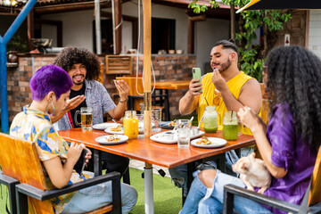 a group of friends from the lgbt community gathering on the terrace of an outdoor restaurant chatting and enjoying the food.