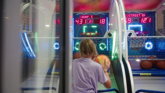Teen boy scoring in moving hoop at arcade