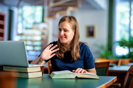 A visually impaired woman with her notebook sitting and studying in the university library
