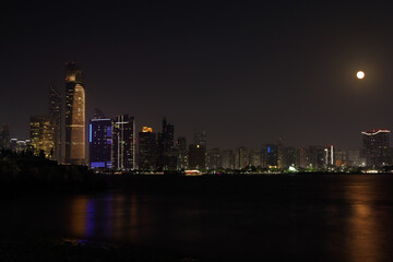 Fototapeta na wymiar Colorful Abu dhabi city skyline at night and rise of full moon