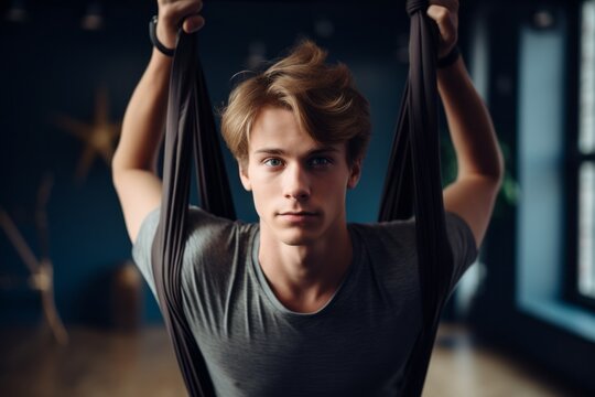 Close-up portrait photography of a tired boy in his 20s doing aerial yoga in a studio. With generative AI technology