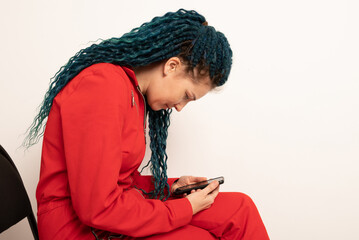 Woman with bad posture using smartphone while sitting on stool near light grey wall indoors, space...