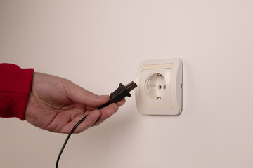 Different standards for electrical outlets. Unsuitable connector and plug in the hand of a person....