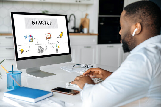 African American young adult successful man sitting at desk with computer, working on new startup, planning idea and strategy