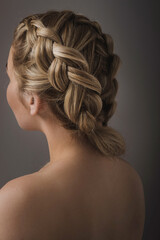 Close-up of a blonde woman's hairstyle, back view from the back on a gray background