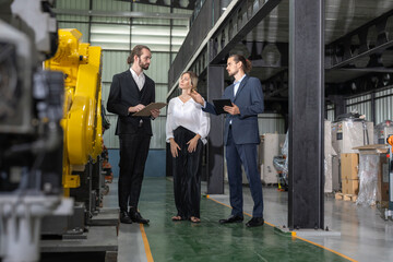 Two businessman visits robot factory. Female owner engineer explaining assembling robot arms welding machine at robotic warehouse factory - obrazy, fototapety, plakaty