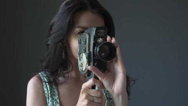 Young woman filmmaker who shoots on a 8mm film retro vintage video camera. Cimema movie concept