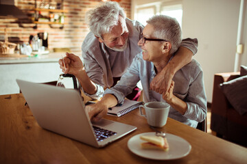 Senior couple using the laptop together at home