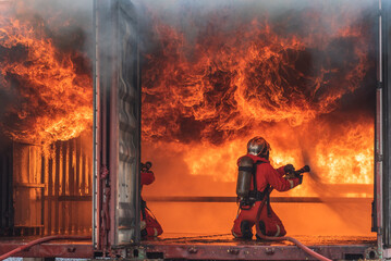 Firemen use extinguisher water fight fire burn during firefight training. Firefighter wearing fire suit for safety danger situation. Fireman work closely with other emergency response agency - obrazy, fototapety, plakaty