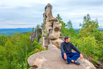 young handsome man on a rock on the Arakul shihan enjoys on a summer day