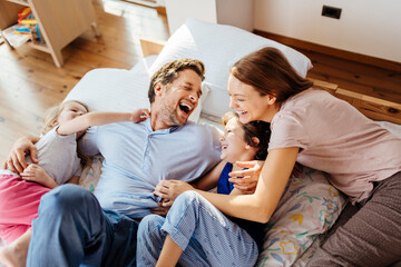 Happy young family playing and having fun on the bed at home
