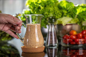homemade sauces of salad dressings and olive oil in small glass jug including Japanese sesame seed. Glass jug of Japanese sesame seed salad dressings and olive oil.