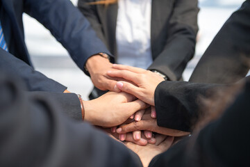 business people putting join hands together. Unity and teamwork show by Stack mix of hands with...