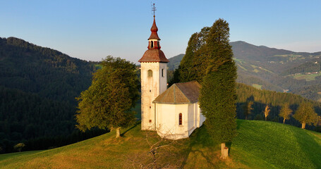 Aerial view of St. Thomas church on top of a hill, early morning sunrise near Skofja Loka, Slovenia