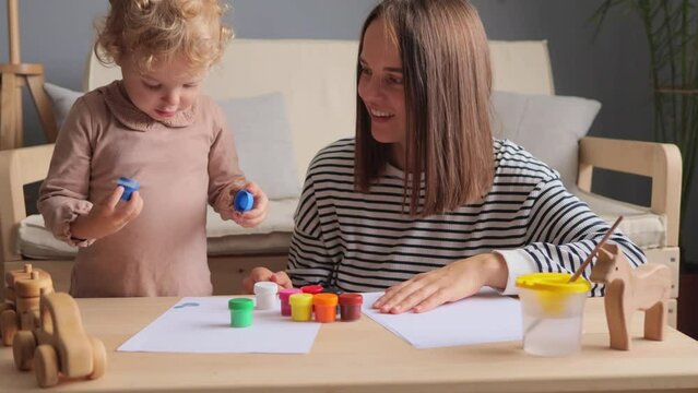 Children at home. Family bonding. Childhood education. Indoor activities. Little kids playing. Baby's development. Happy mother with her little baby daughter painting together in home interior