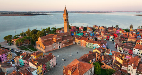Aerial view of Burano Island, colorful houses, Church of Saint Martin Bishop and Campanile at sunrise golden hour, Venice, Veneto Region, Italy