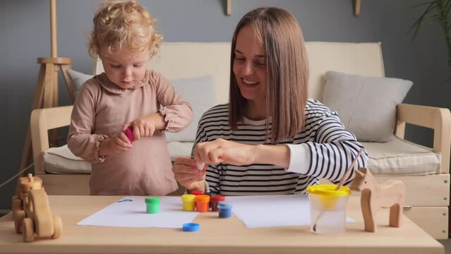 Little child playing. Parenting together. Preschool creativity. Colorful toys. Teaching moments. Creative games. Cheerful woman with her toddler toddler kid drawing together at home