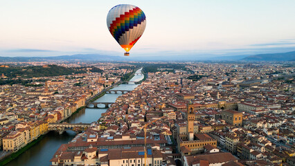 Florence, Colorful hot air balloon epic flying above the city at sunrise, Cathedral of Saint Mary of the Flower, Palazzo Vecchio, Ponte Vecchio, Italy