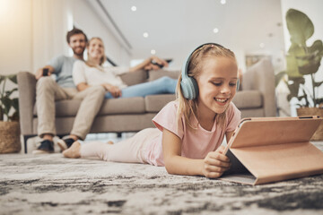 Child, headphones and tablet on floor in home education, listening to audio and streaming with...