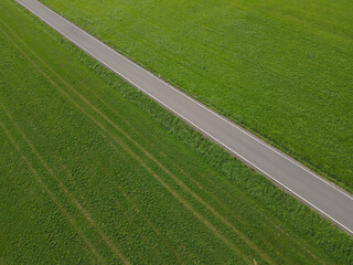 Obraz premium Aerial view of a road between grass fields in the landscape 
