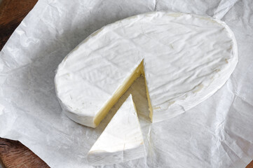 Soft brie cheese close up on paper, top view, selective focus in daylight