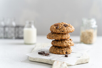 Homemade oatmeal cookies with banana, oats, nuts and chocolate drops on a wooden board on light background. Side view, copy space for text. Healthy food. Oatmeat biscuits. Horizontal