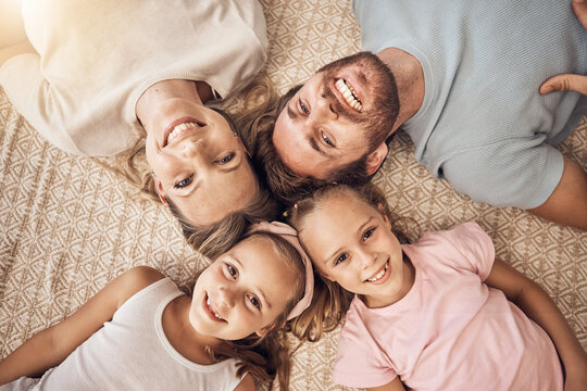 Love, portrait and top view of happy family on a floor bonding, relax and having fun at home together. Face, smile and children with parents lying in a living room with care, support or security