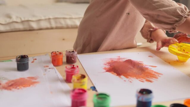 Funny art. Toddler's creativity. Unknown infant child drawing with colorful fingers at home or nursery little artist preschooler having fun painting child creating lovely image.