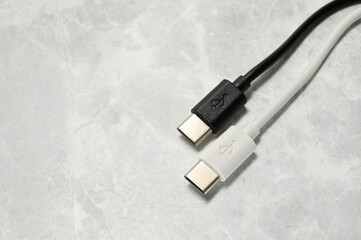 White and Black USB Type-C charger cable on a light stone background.